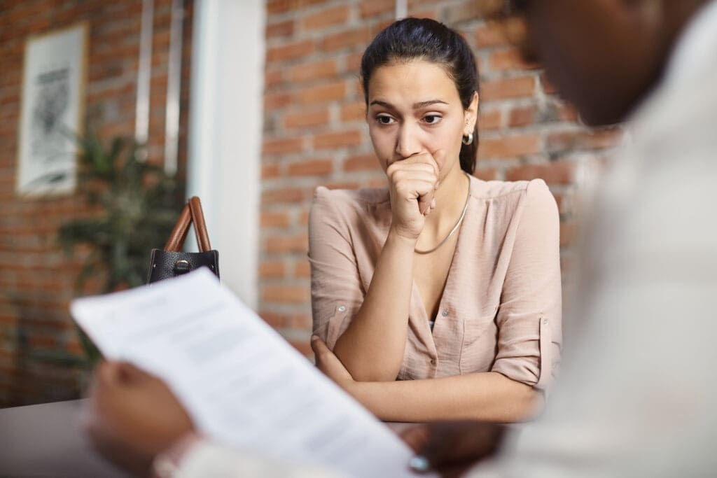 A woman looking nervous in a performance review meeting with her manager. Credit: https://www.istockphoto.com/portfolio/DrazenZigic?mediatype=photography