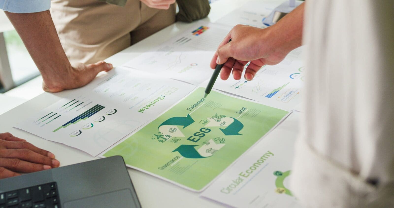 A team working on ESG documents around a table. Credit: https://www.istockphoto.com/portfolio/Tirachard?mediatype=photography