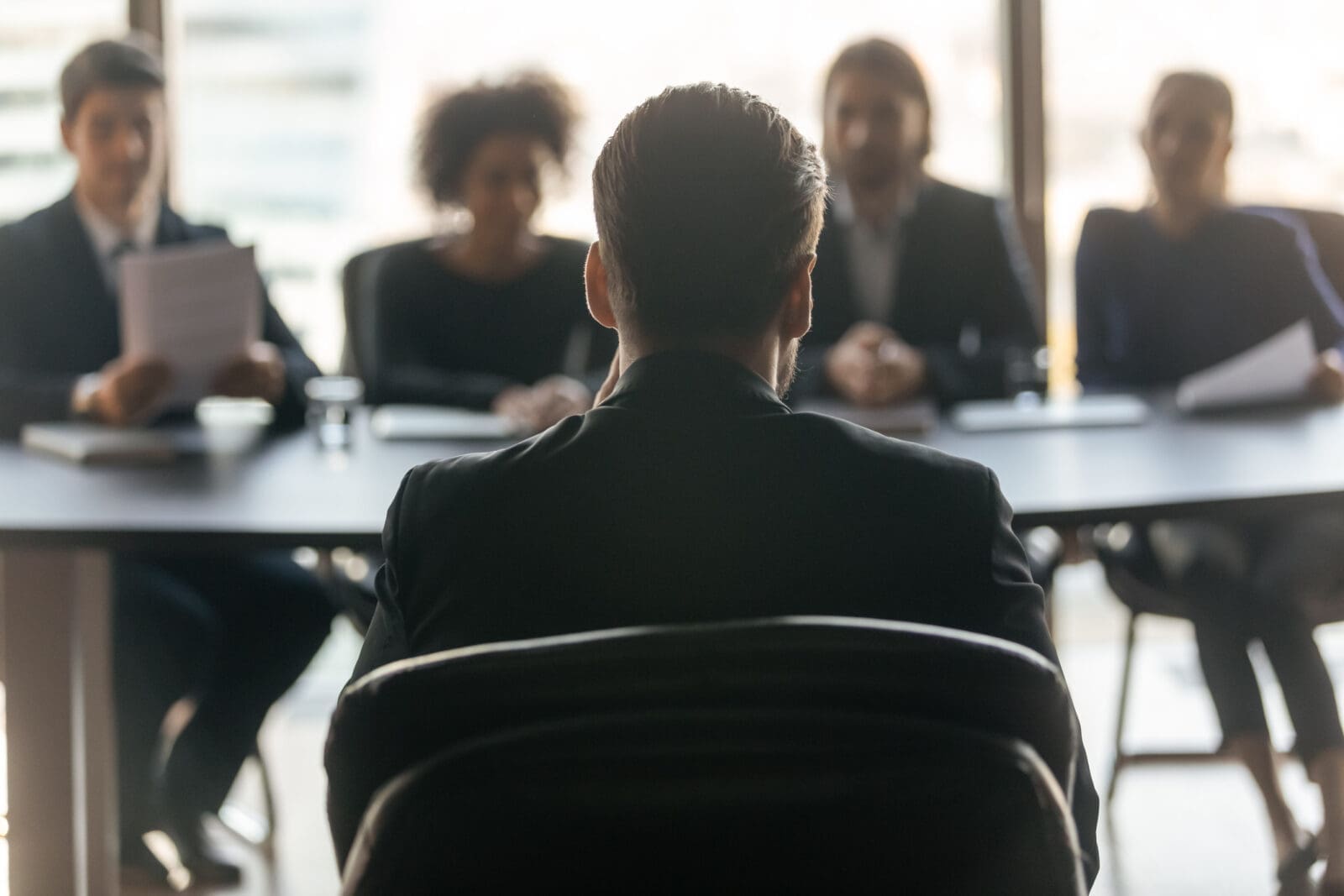A manager sitting across from scrutinizing stakeholders. CREDIT: https://www.istockphoto.com/portfolio/fizkes