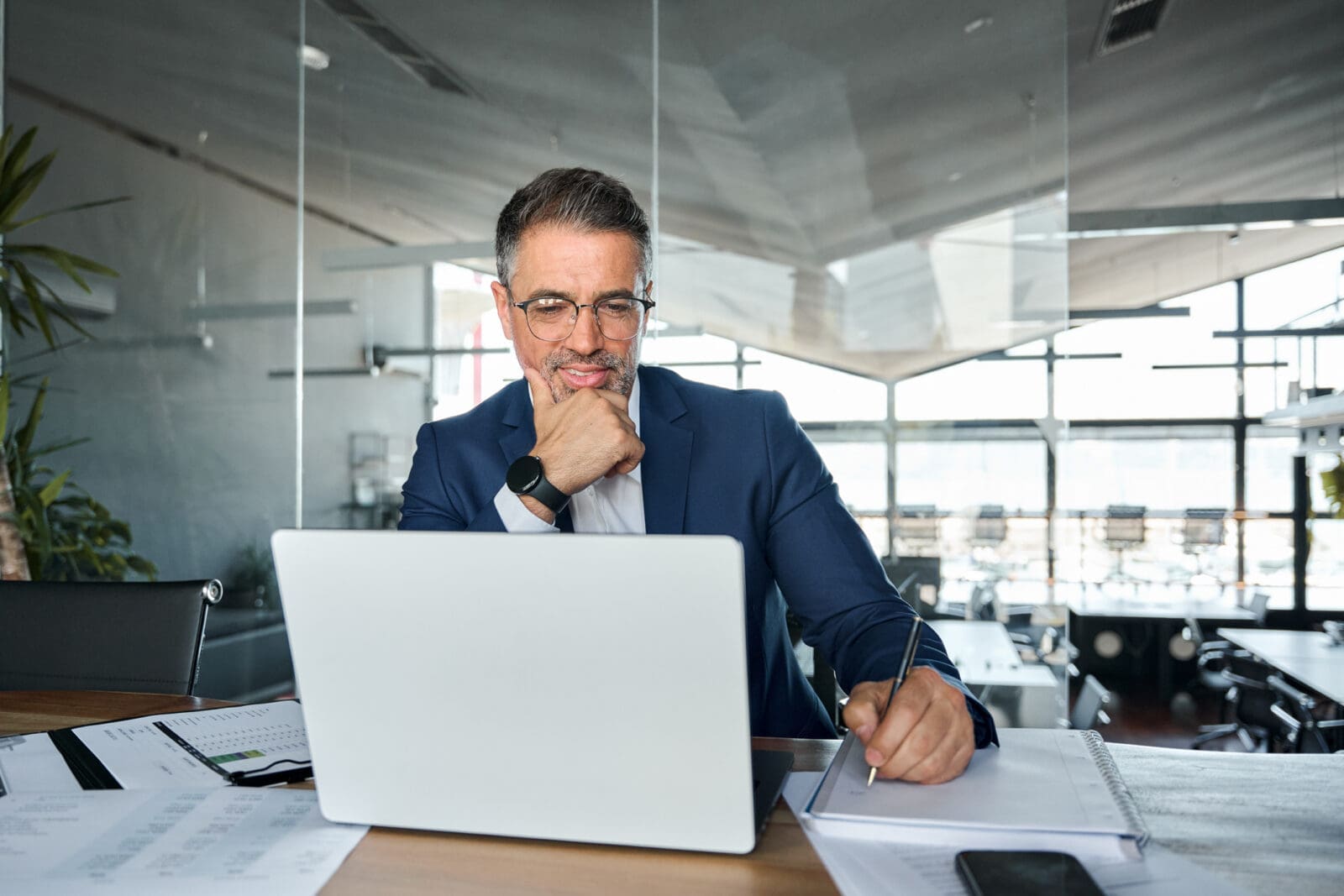 Mature male leader watching a webcast on his laptop. CREDIT: https://www.istockphoto.com/portfolio/insta_photos
