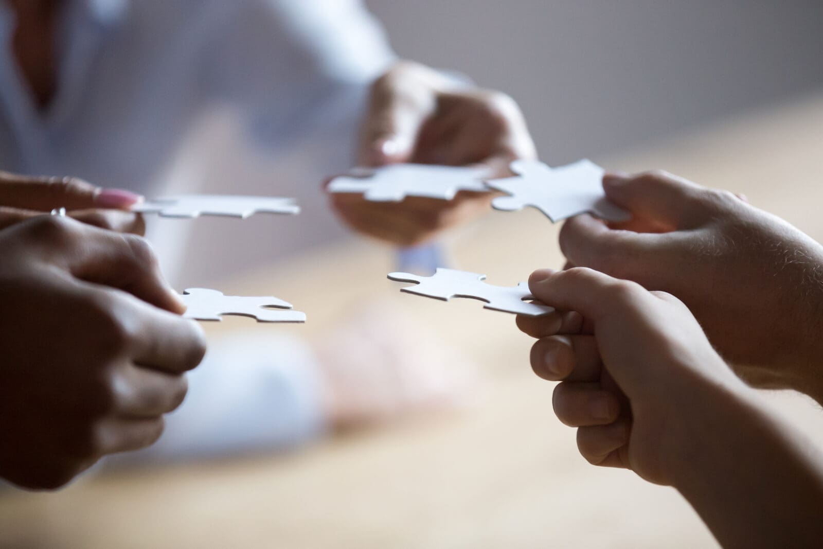 Team members trying to fit puzzle pieces together, as a metaphor for creating OKR alignment. CREDIT: https://www.istockphoto.com/portfolio/fizkes