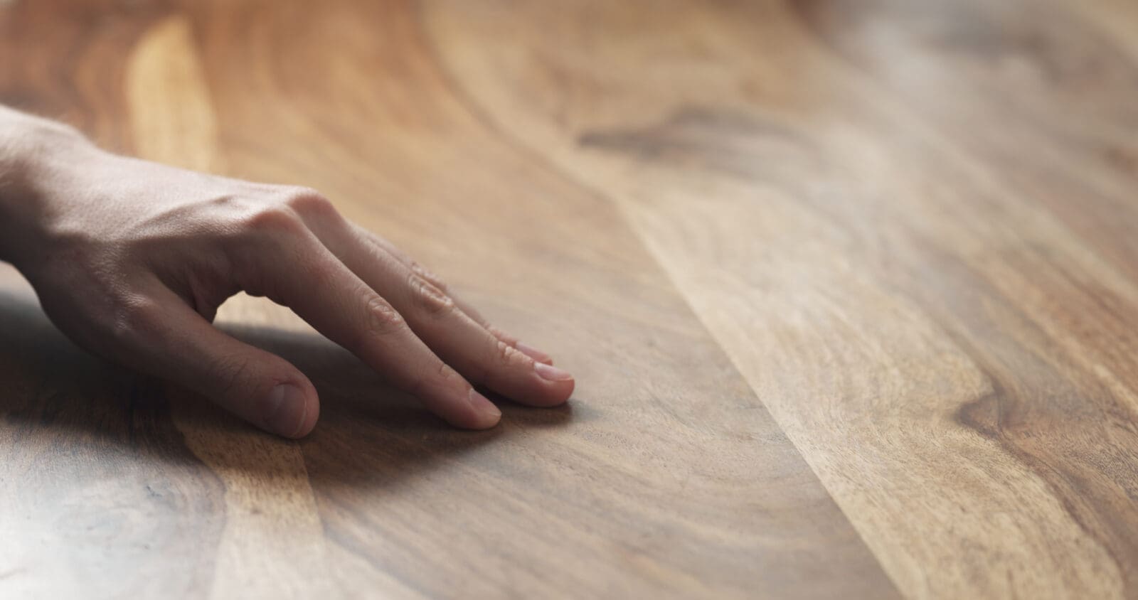 Closeup of man's hand checking a wood surface. CREDIT: https://www.istockphoto.com/portfolio/GooDween123