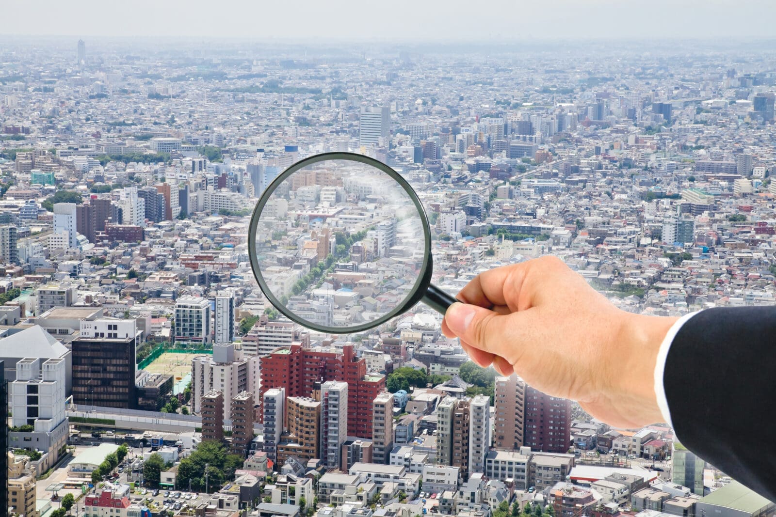 Cityscape view through magnifying glass. CREDIT: https://www.istockphoto.com/portfolio/NAGAHISA_MIMURA
