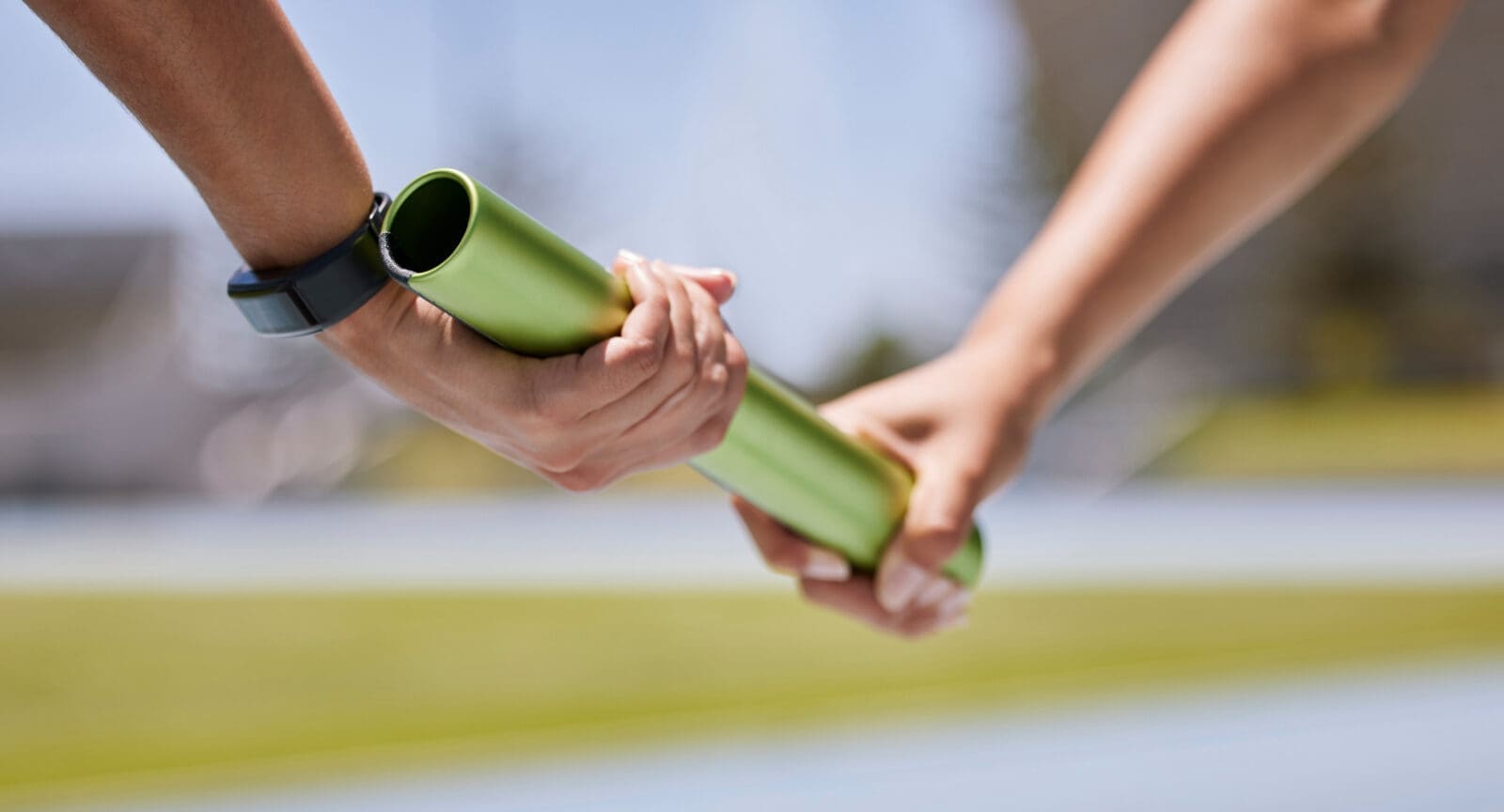 Handing over a baton in a race. CREDIT: https://www.istockphoto.com/portfolio/PeopleImages
