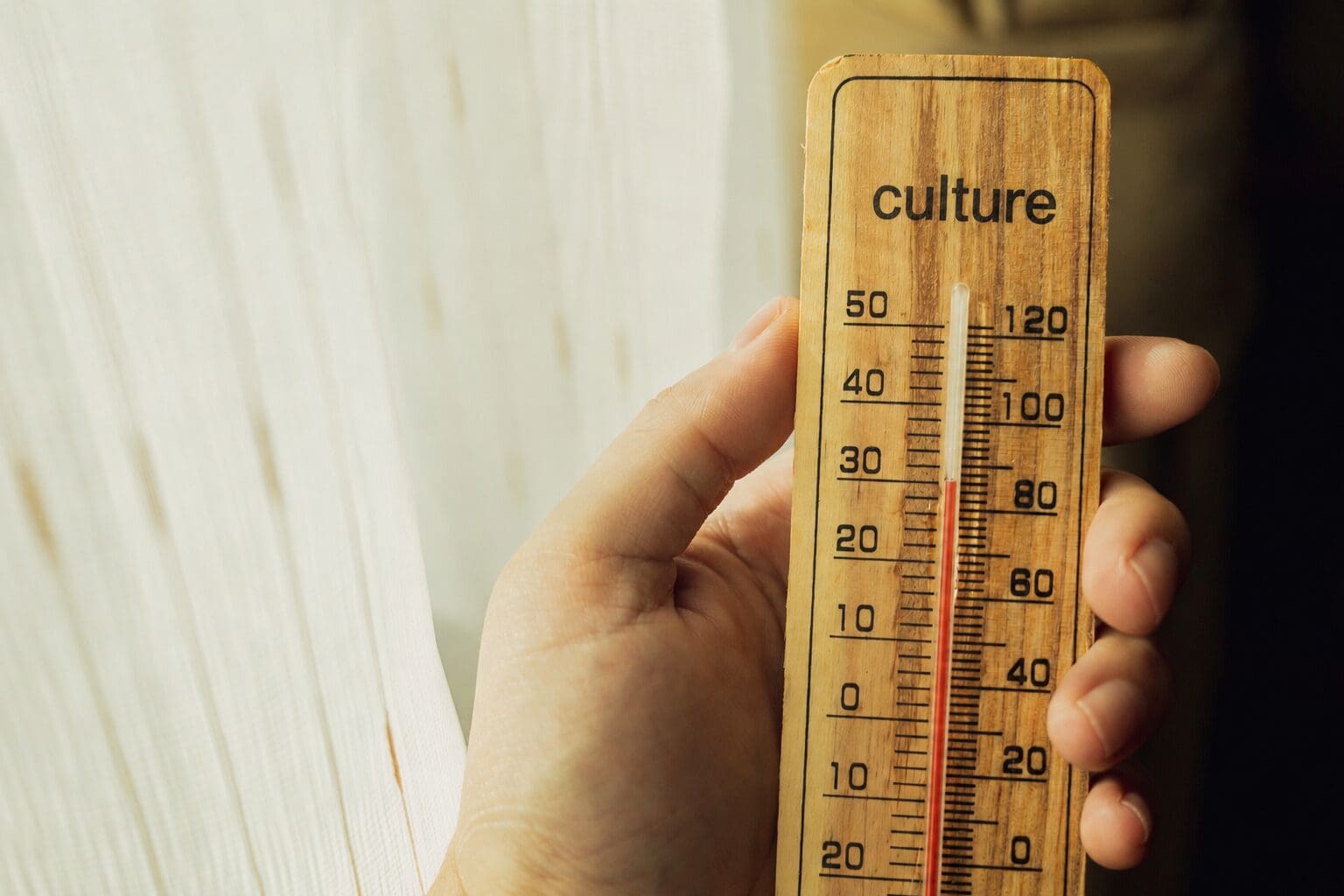 A man's hand holding a wooden thermometer measuring culture. CREDIT: https://www.istockphoto.com/portfolio/Elsaa