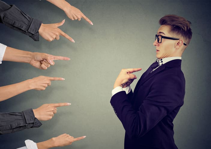 An employee with several fingers pointing at him in blame. CREDIT: https://www.istockphoto.com/portfolio/SIphotography