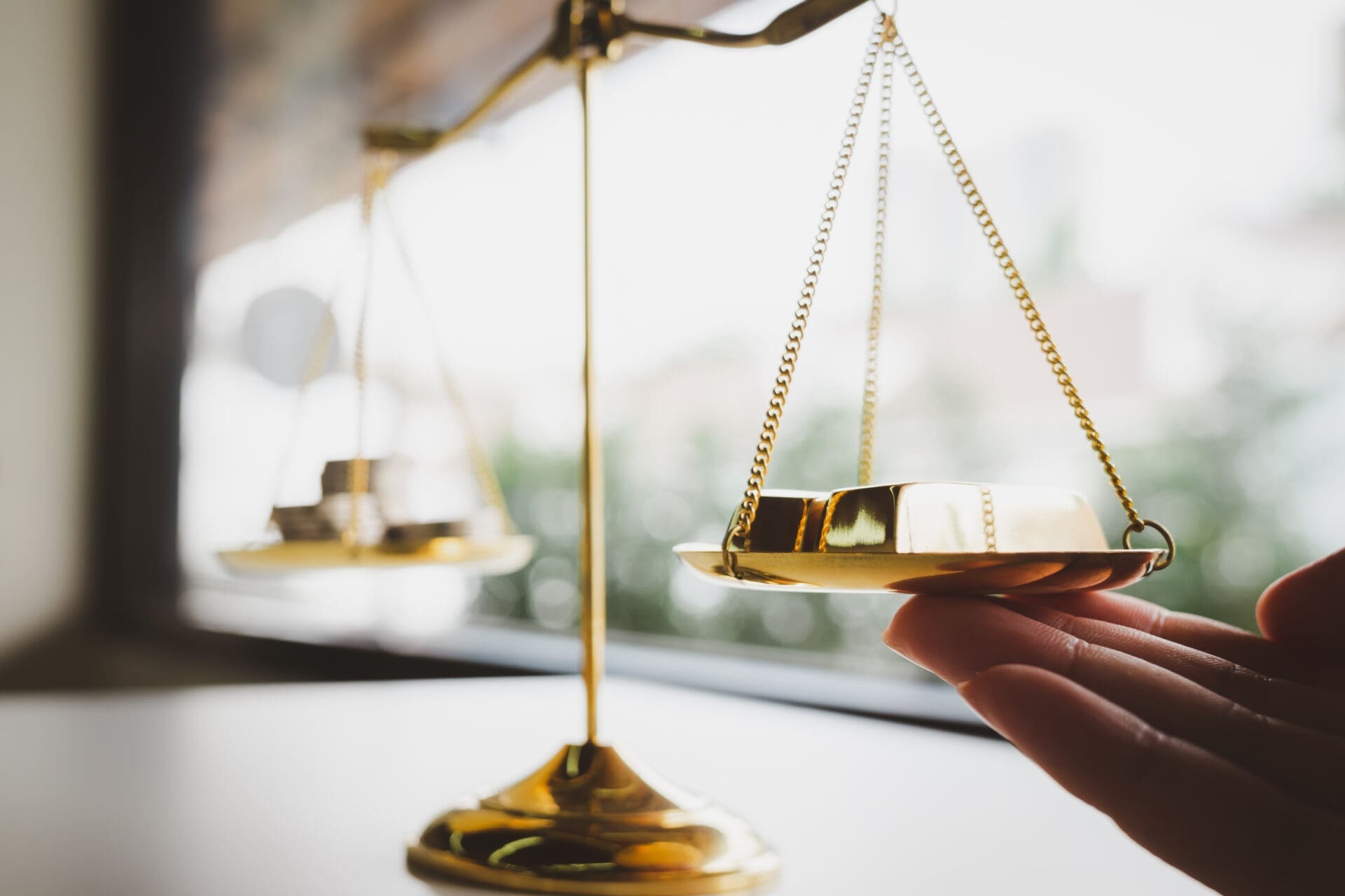 Hand adding gold to one side of a balance scale. CREDIT: https://www.istockphoto.com/portfolio/sommart